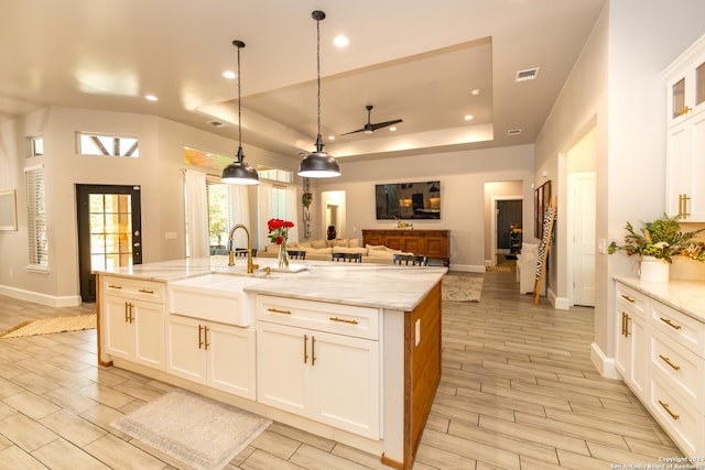 kitchen featuring a center island with sink, white cabinets, and a tray ceiling