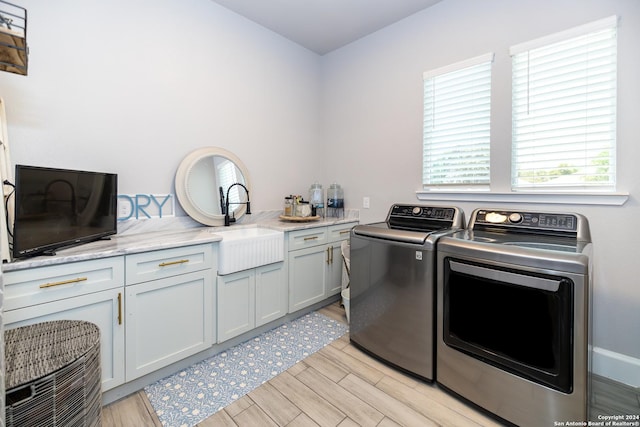 laundry area featuring separate washer and dryer, sink, cabinets, and light wood-type flooring