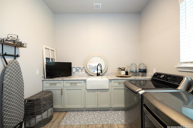 laundry room featuring sink, light hardwood / wood-style floors, cabinets, and washing machine and clothes dryer