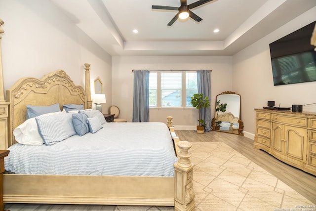 bedroom with a tray ceiling, light hardwood / wood-style flooring, and ceiling fan