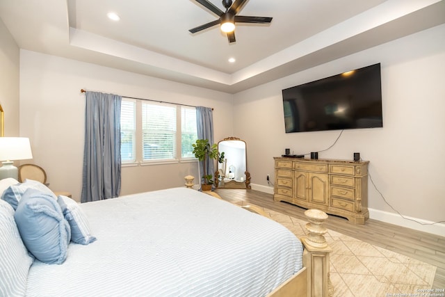 bedroom featuring light hardwood / wood-style floors, a raised ceiling, and ceiling fan