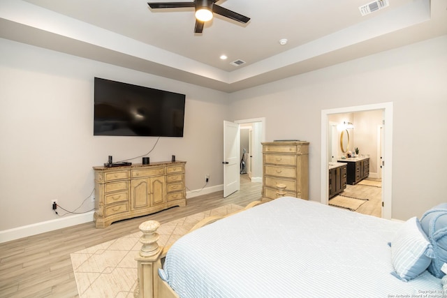 bedroom featuring ensuite bathroom, hardwood / wood-style floors, ceiling fan, and a tray ceiling