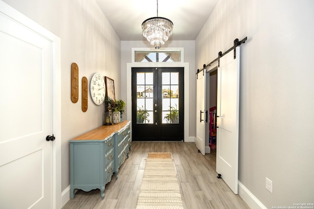 doorway to outside featuring a notable chandelier, light hardwood / wood-style floors, french doors, and a barn door