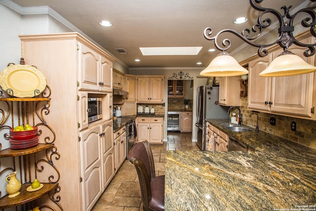 kitchen with a skylight, sink, ornamental molding, stainless steel appliances, and light brown cabinets