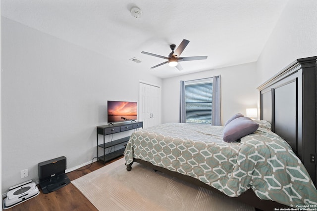 bedroom with dark wood-type flooring, ceiling fan, and a closet