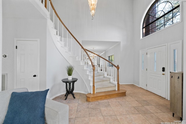 tiled foyer entrance with a high ceiling, plenty of natural light, and a chandelier