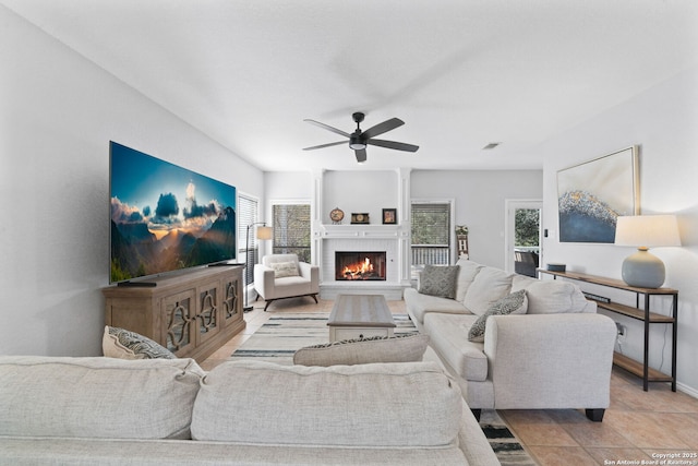 living room featuring a brick fireplace, light tile patterned floors, plenty of natural light, and ceiling fan