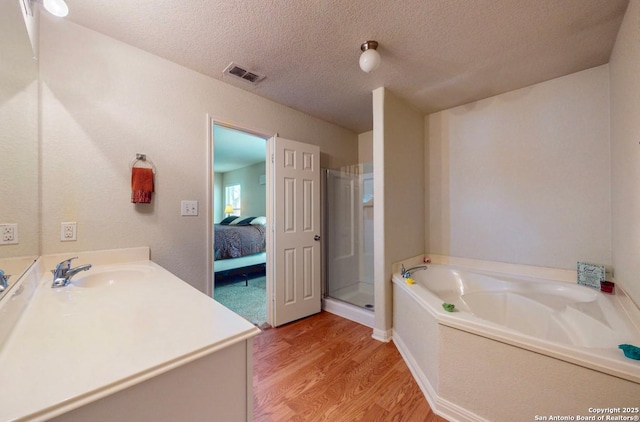 bathroom with vanity, hardwood / wood-style floors, independent shower and bath, and a textured ceiling