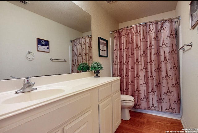 full bathroom with vanity, hardwood / wood-style floors, a textured ceiling, and shower / bath combo with shower curtain