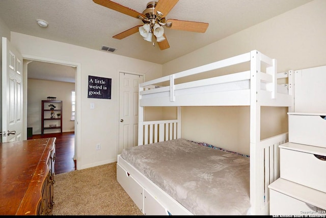 bedroom with ceiling fan, carpet flooring, and a textured ceiling