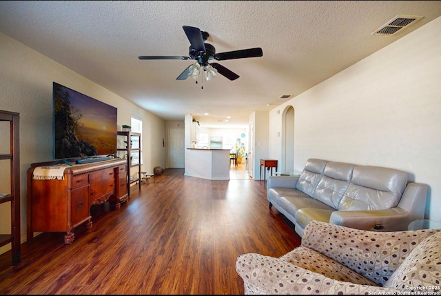 living room featuring dark hardwood / wood-style flooring, ceiling fan, and a textured ceiling