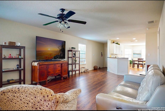 living room featuring ceiling fan, dark hardwood / wood-style floors, and a textured ceiling