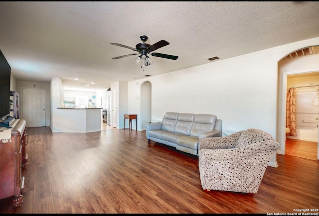 living room with ceiling fan, dark hardwood / wood-style floors, and a textured ceiling