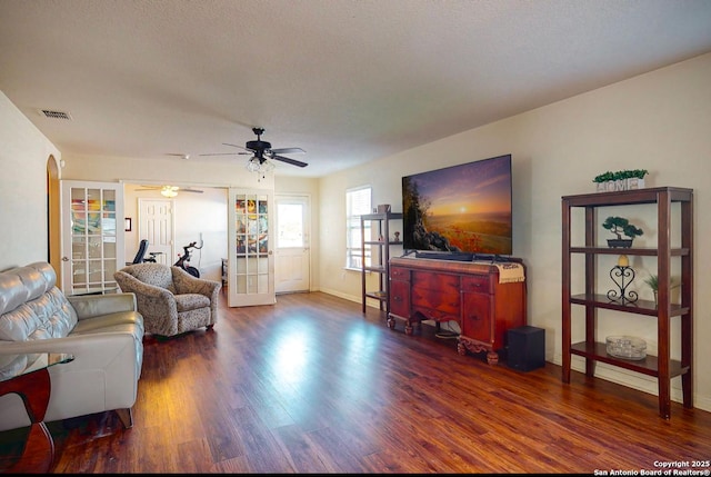 living room with ceiling fan, dark wood-type flooring, french doors, and a textured ceiling