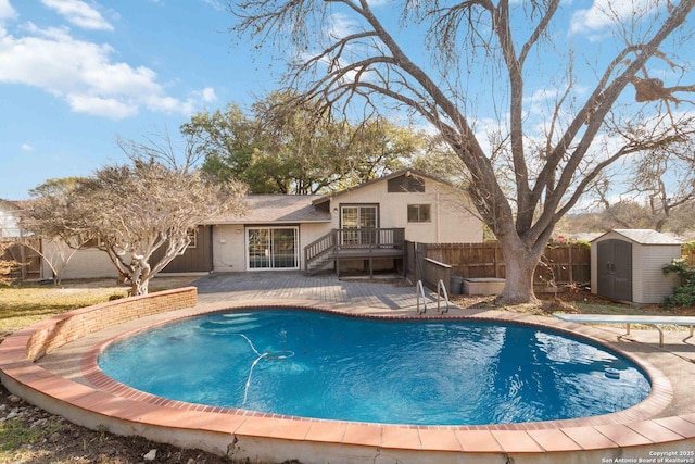 view of swimming pool with a storage shed and a diving board