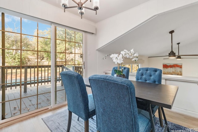 dining space with lofted ceiling, wood-type flooring, and ceiling fan with notable chandelier