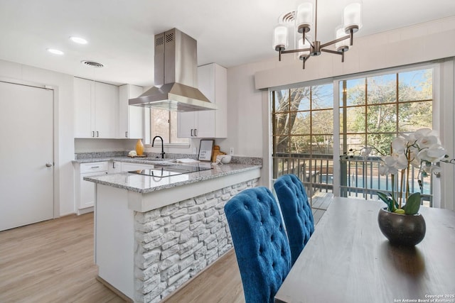 kitchen with white cabinetry, island range hood, and light stone countertops