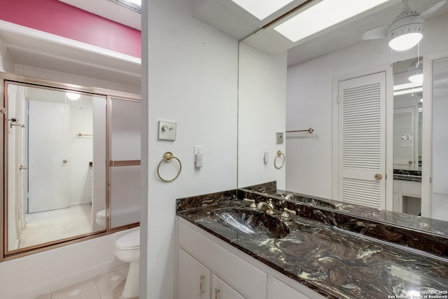 full bathroom featuring enclosed tub / shower combo, tile patterned flooring, a skylight, vanity, and toilet