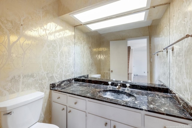 bathroom with vanity, toilet, and a skylight