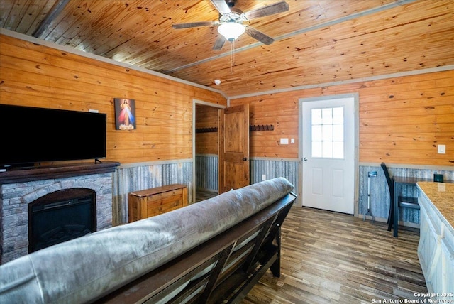 living room featuring a stone fireplace, dark wood-type flooring, wooden ceiling, and ceiling fan