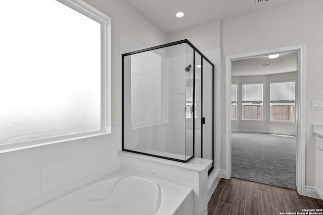 bathroom with wood-type flooring, shower with separate bathtub, and vanity