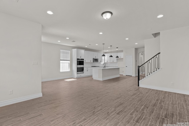 unfurnished living room with sink and light hardwood / wood-style floors