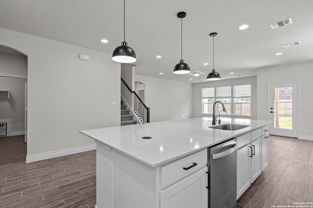 kitchen with stainless steel dishwasher, sink, a center island with sink, and white cabinets