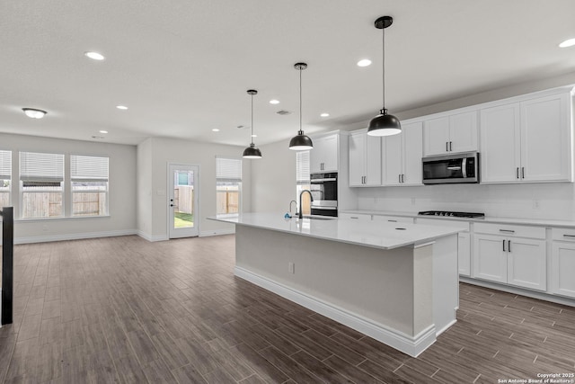 kitchen featuring white cabinetry, appliances with stainless steel finishes, a center island with sink, and pendant lighting