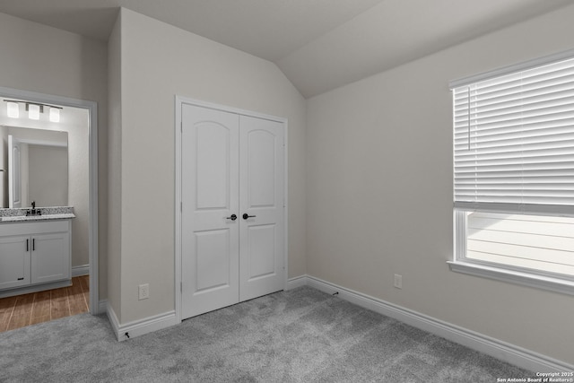 unfurnished bedroom with vaulted ceiling, light carpet, and a closet