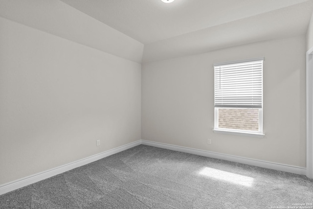 carpeted spare room with vaulted ceiling