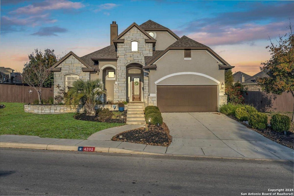 french country inspired facade with a garage and a lawn