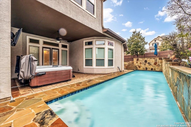 view of swimming pool with ceiling fan and a hot tub