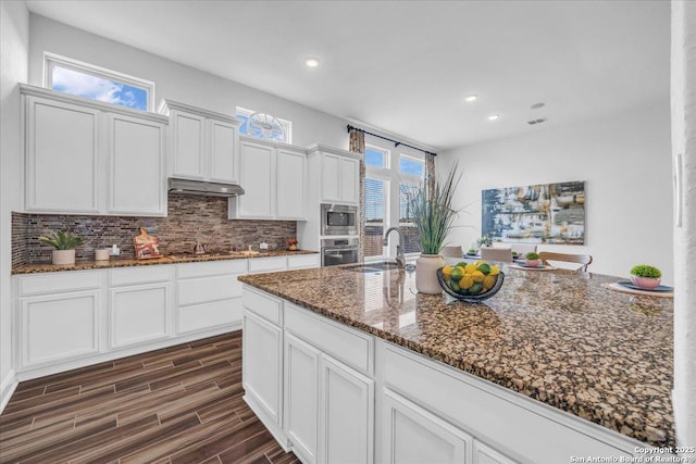 kitchen with sink, dark stone countertops, white cabinets, backsplash, and stainless steel appliances