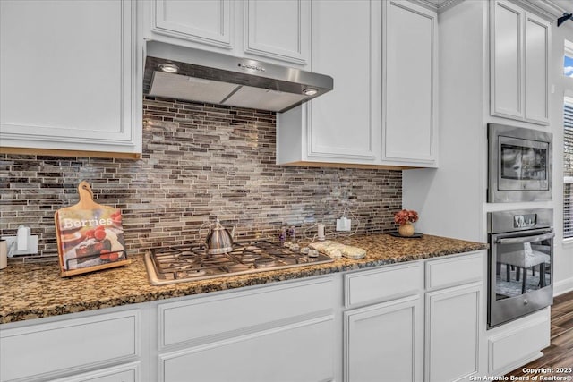 kitchen with dark stone countertops, stainless steel appliances, and white cabinets