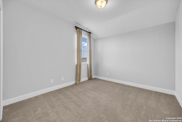 carpeted empty room featuring lofted ceiling