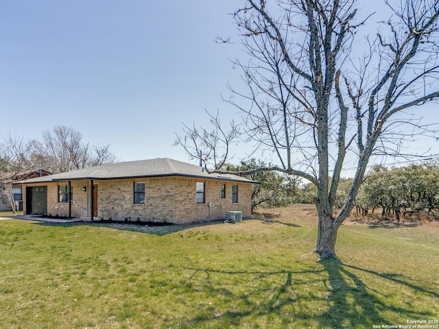 view of front of house featuring brick siding, an attached garage, central AC, and a front yard