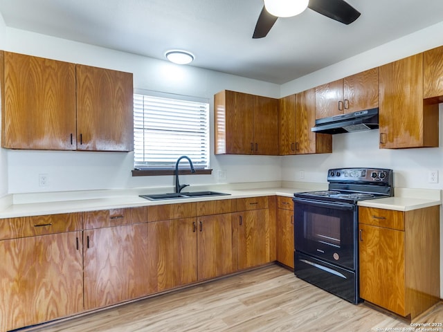 kitchen featuring light countertops, black range with electric stovetop, under cabinet range hood, and a sink