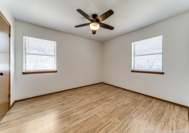 spare room featuring a ceiling fan, a healthy amount of sunlight, light wood-type flooring, and baseboards