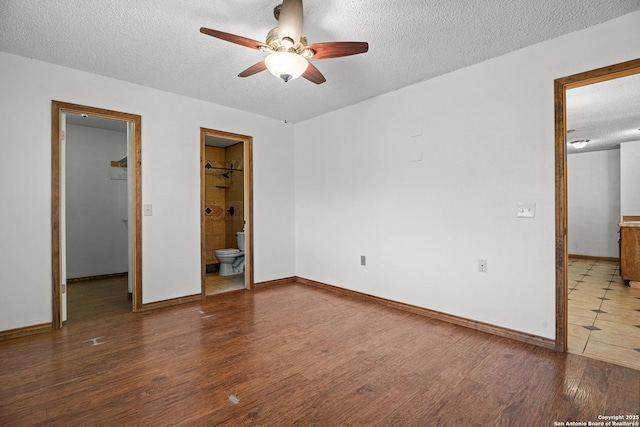 unfurnished bedroom featuring ceiling fan, ensuite bath, wood-type flooring, and a textured ceiling