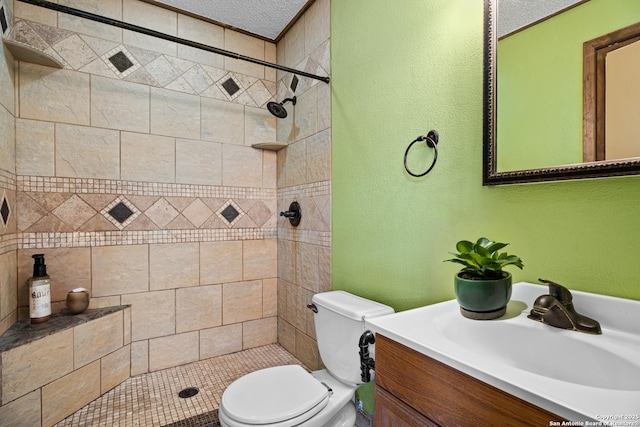 bathroom with tiled shower, vanity, toilet, and a textured ceiling