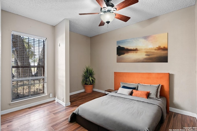 bedroom featuring ceiling fan, hardwood / wood-style flooring, and a textured ceiling