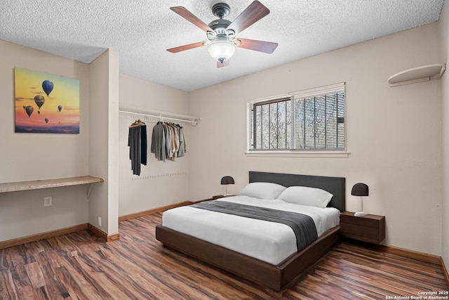 bedroom with dark hardwood / wood-style floors, built in desk, a closet, and a textured ceiling