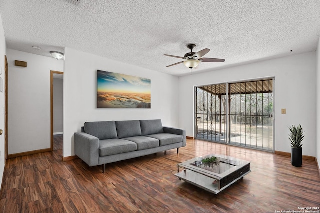 living room featuring ceiling fan, dark hardwood / wood-style flooring, and a textured ceiling