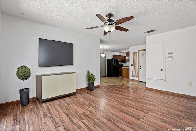 unfurnished living room featuring a textured ceiling, wood-type flooring, and ceiling fan