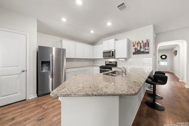 kitchen featuring sink, white cabinetry, appliances with stainless steel finishes, a kitchen breakfast bar, and kitchen peninsula