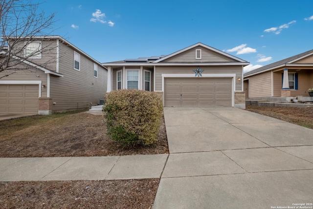 ranch-style home featuring an attached garage, solar panels, and driveway