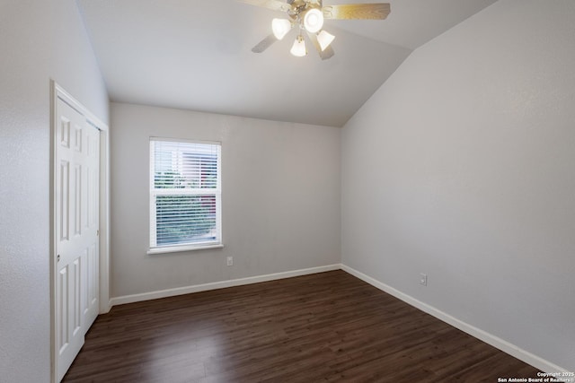 unfurnished bedroom with dark wood finished floors, a closet, baseboards, and vaulted ceiling