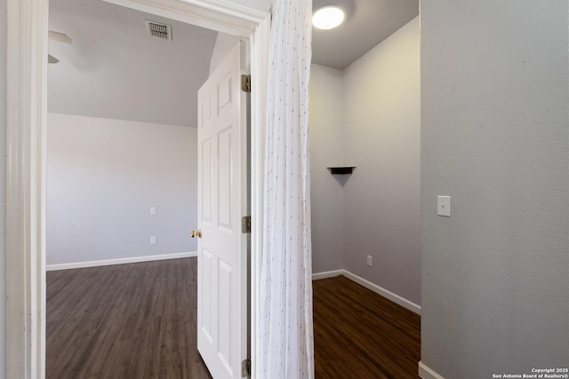 hall featuring visible vents, baseboards, and dark wood-type flooring