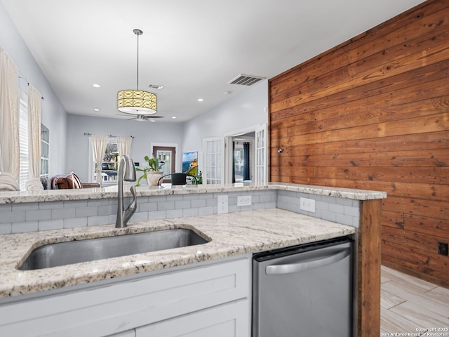 kitchen with sink, dishwasher, hanging light fixtures, light stone counters, and white cabinets