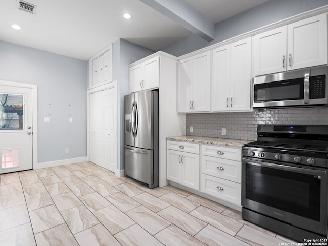 kitchen featuring appliances with stainless steel finishes, tasteful backsplash, white cabinets, light stone counters, and beam ceiling